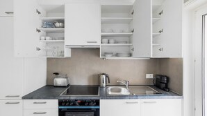 Eine moderne Küche mit weißen Schränken, einer schwarzen Arbeitsplatte, einem Einbauofen, einem Spülbecken und einer Kaffeemaschine.