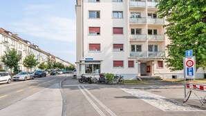 Ein mehrgeschossiges Wohngebäude mit Balkonen, einem Parkschild und einem Fahrrad davor.