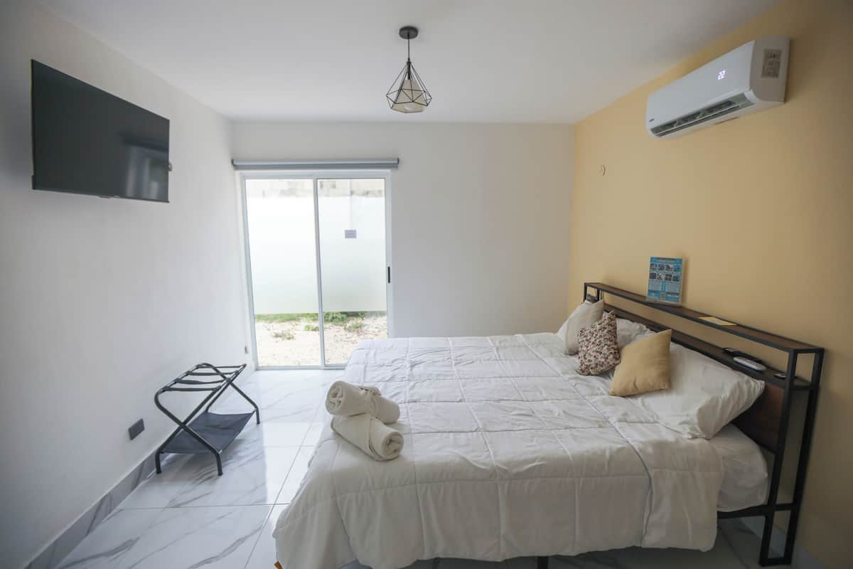 Habitación de hotel con cama, televisor en la pared, aire acondicionado y ventana con vista al exterior.