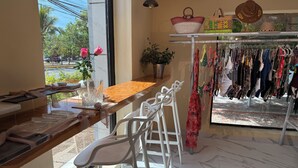 A boutique with a clothing rack, a wooden table, and a seating area with white chairs. - Downtown Suites - Hotel Boutique by Maraf (Cancún)
