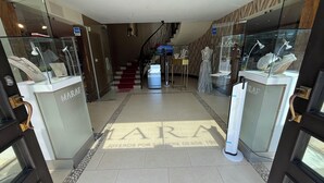 A hotel lobby with a staircase, glass display cases, and a tiled floor. - Downtown Suites - Hotel Boutique by Maraf (Cancún)