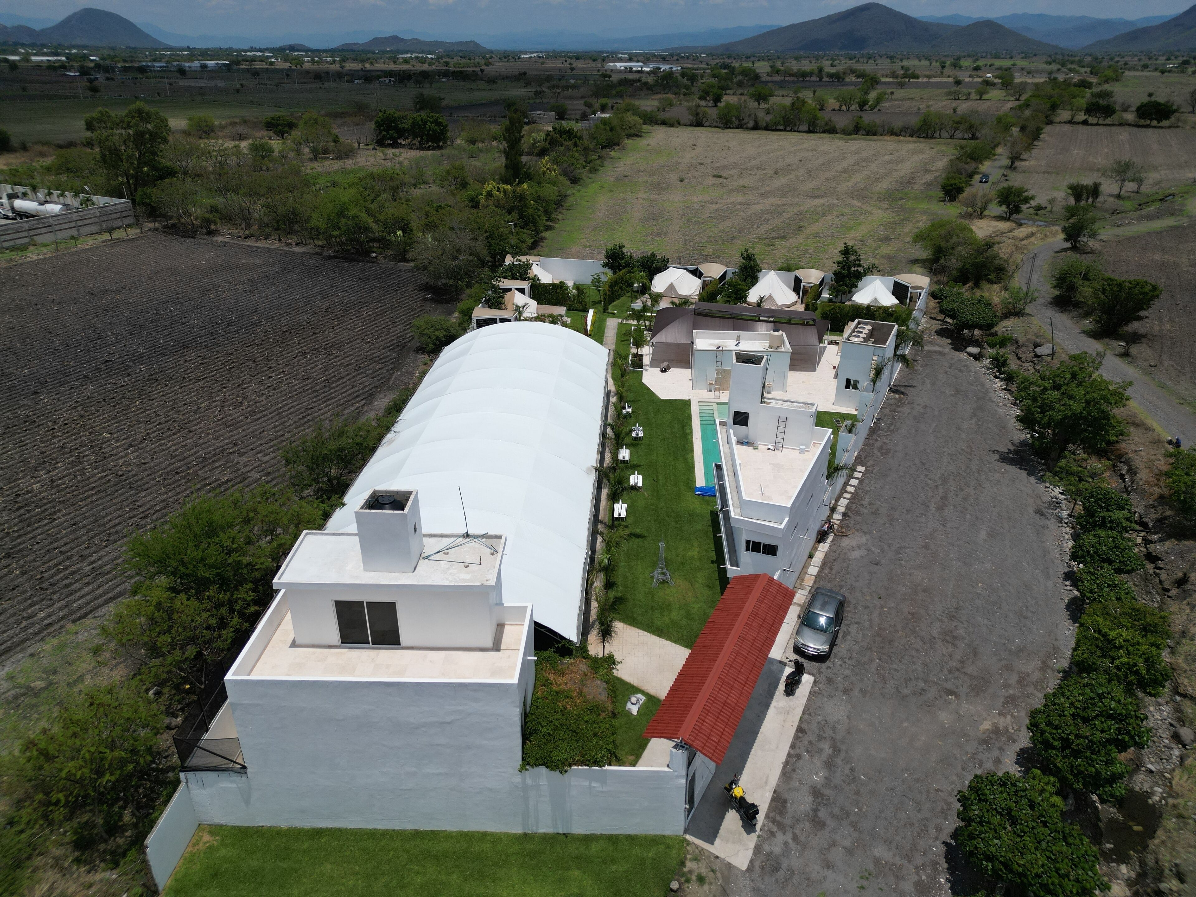 A modern residential area with multiple houses, a swimming pool, and a paved road.