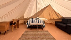 Een tent met een bed, een stoel, een bank en een kleine tafel.