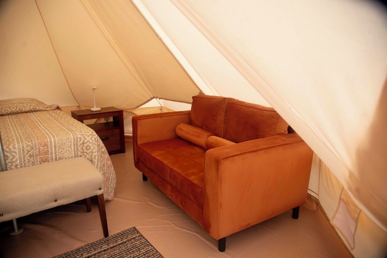 A tent with a bed and a sofa.