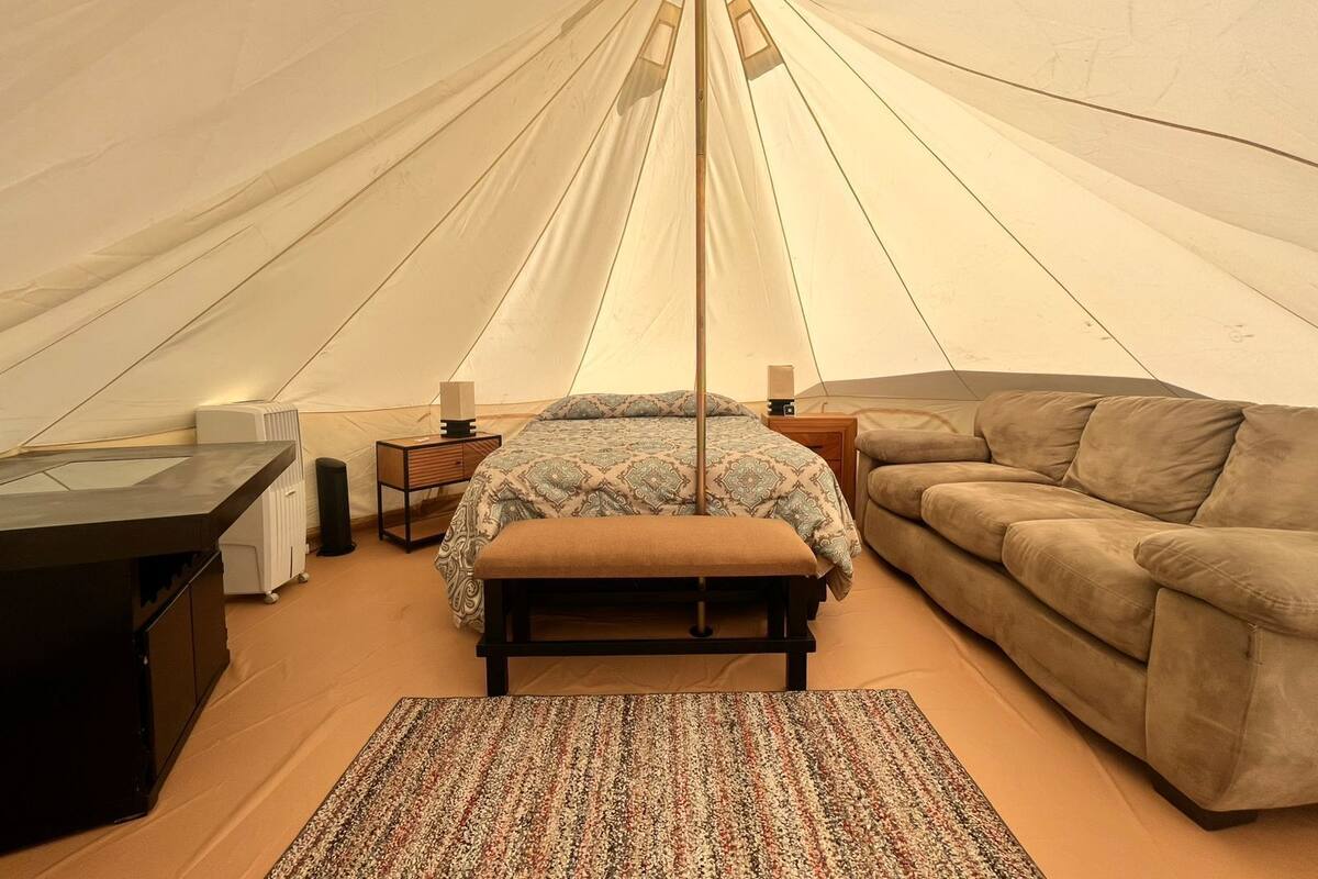 Une tente équipée d’un lit, d’un canapé, d’une table et d’un tapis.