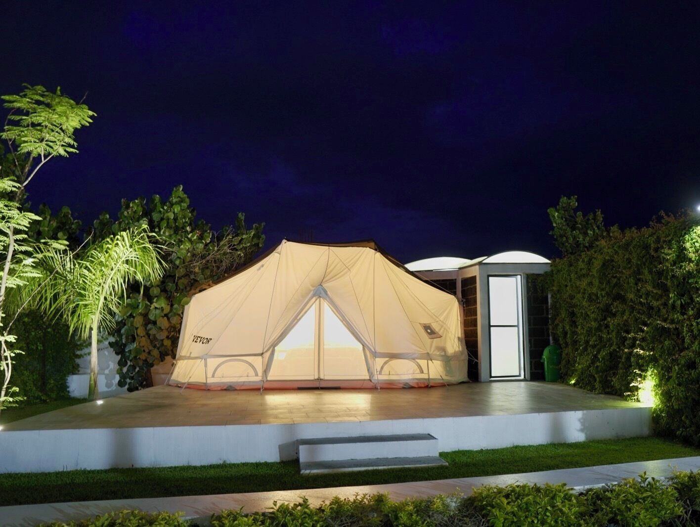 A tent with a transparent front, a door, and a small attached structure.