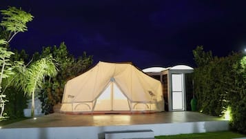A tent with a transparent front, a door, and a small attached structure.
