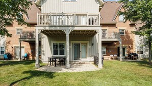 A two-story building with a covered patio area featuring a table and chairs.