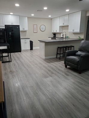A modern kitchen with white cabinets, a black refrigerator, and a wooden floor. - Cozy/ family place Tampa, centrally located! (Tampa)