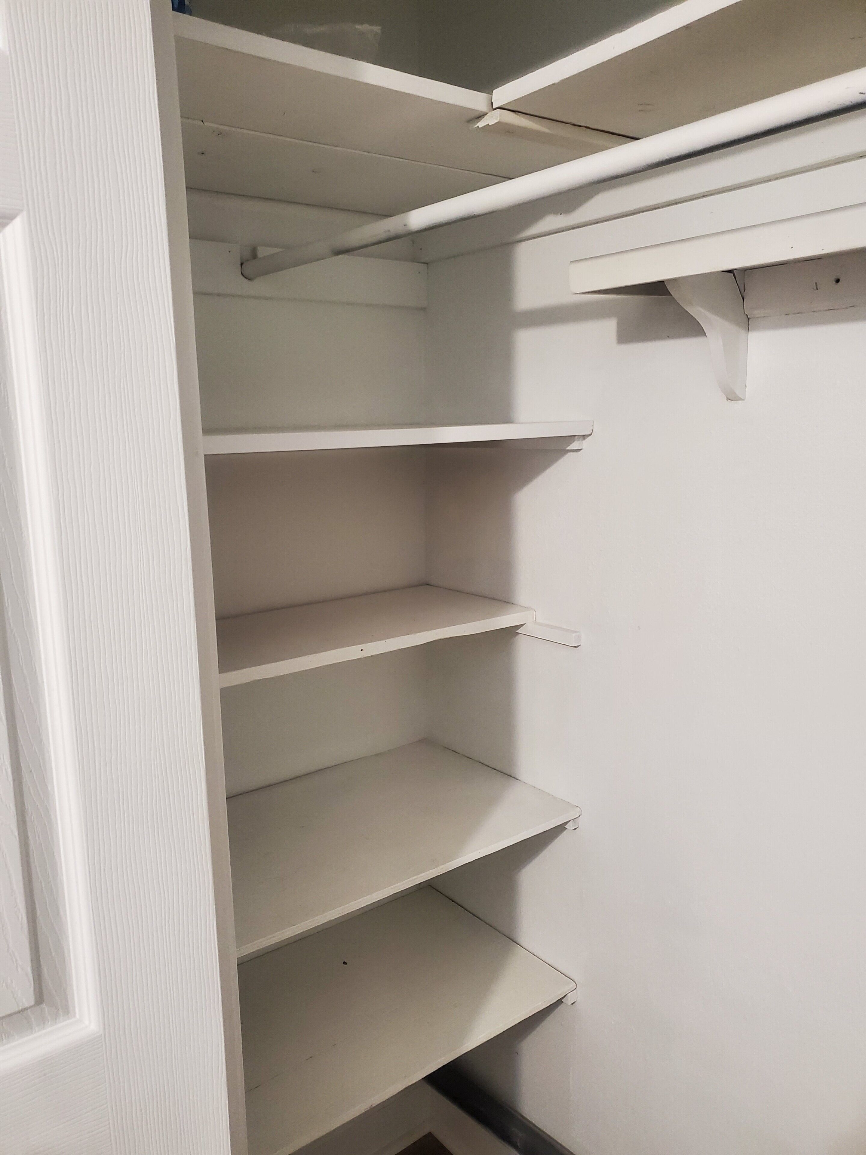 Vista interna de um armário com várias prateleiras e espaço para pendurar roupas.