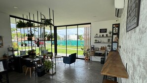 Una habitación amplia con un gran ventanal corredero que da a un balcón, un comedor con mesa y sillas, y una zona de bar con taburetes.