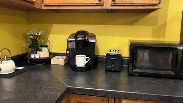 A kitchen with wooden cabinets, a coffee maker, a toaster, a kettle, and a microwave.