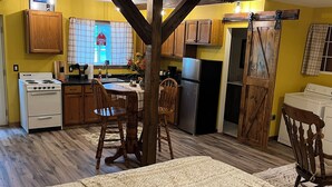 A kitchen with wooden cabinets, a stove, and a refrigerator. - The Little Red Barn (Cedar Falls)