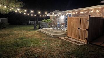 A backyard with a covered patio area, a wooden deck, and string lights.