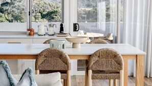 Une cuisine moderne dotée d'un grand îlot central, de chaises en osier et offrant une vue sur l'extérieur.