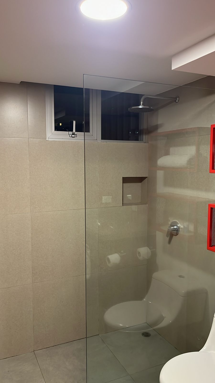 A modern bathroom with a glass-enclosed shower, a toilet, and a sink.