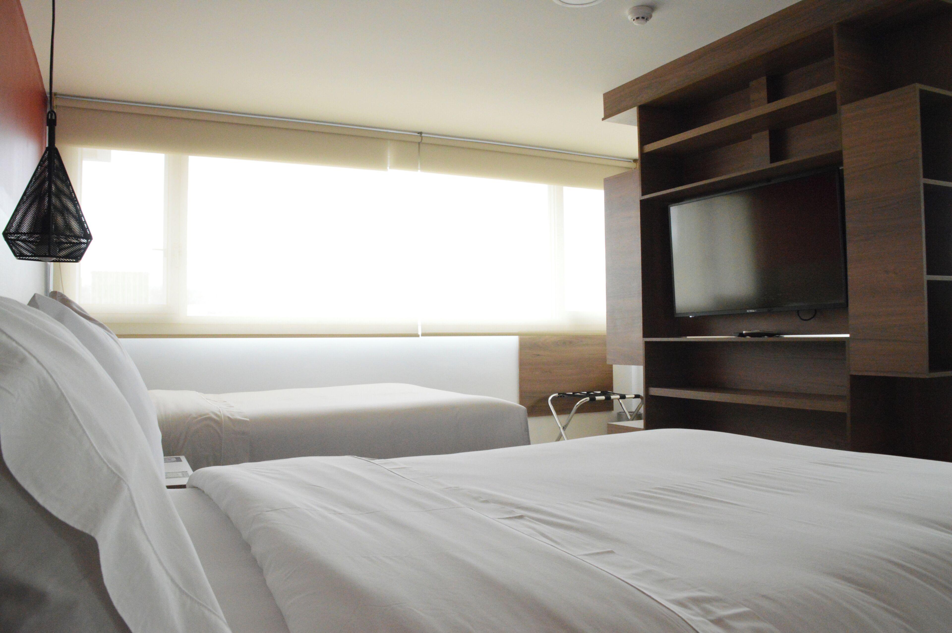 Habitación de hotel con dos camas, un televisor y una ventana con persianas.