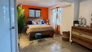 Un dormitorio con cama, cómoda, planta en maceta y ventana con cortinas.