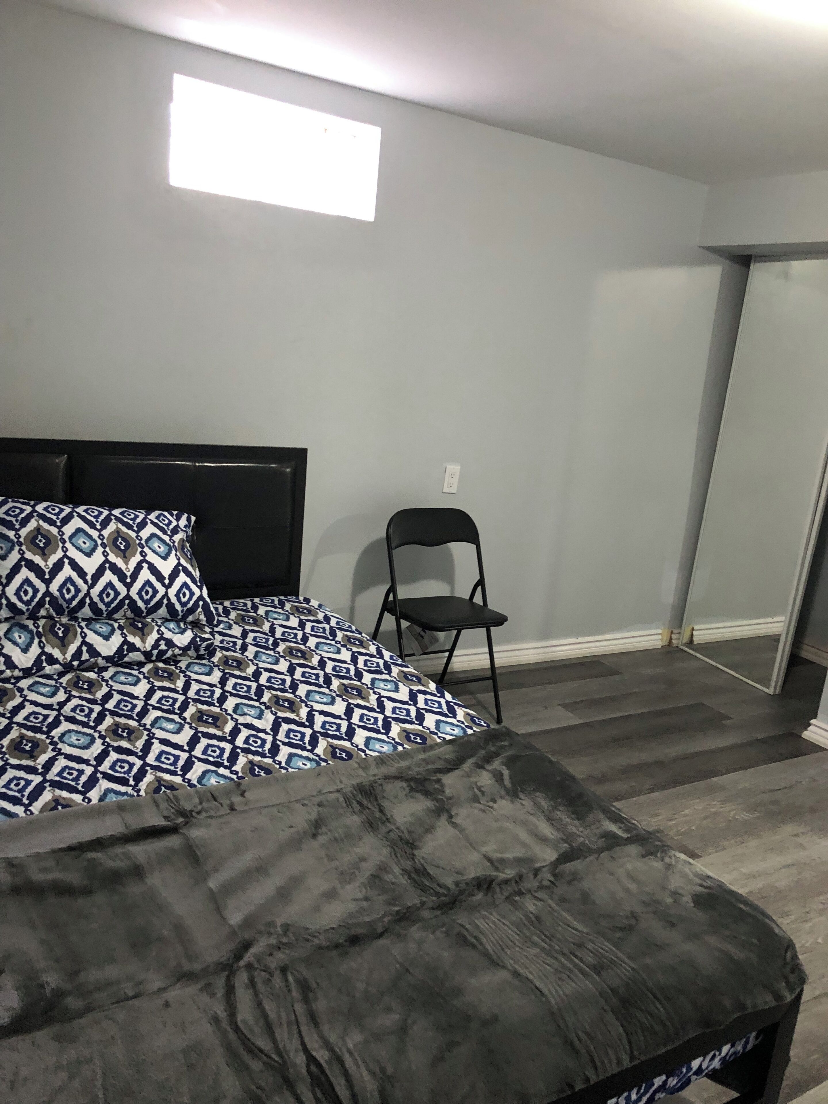Ein Schlafzimmer mit einem Bett, einem Sessel und einem kleinen Fenster.