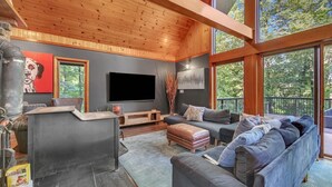 A modern living room with a large TV, dark sofas, and a fireplace.