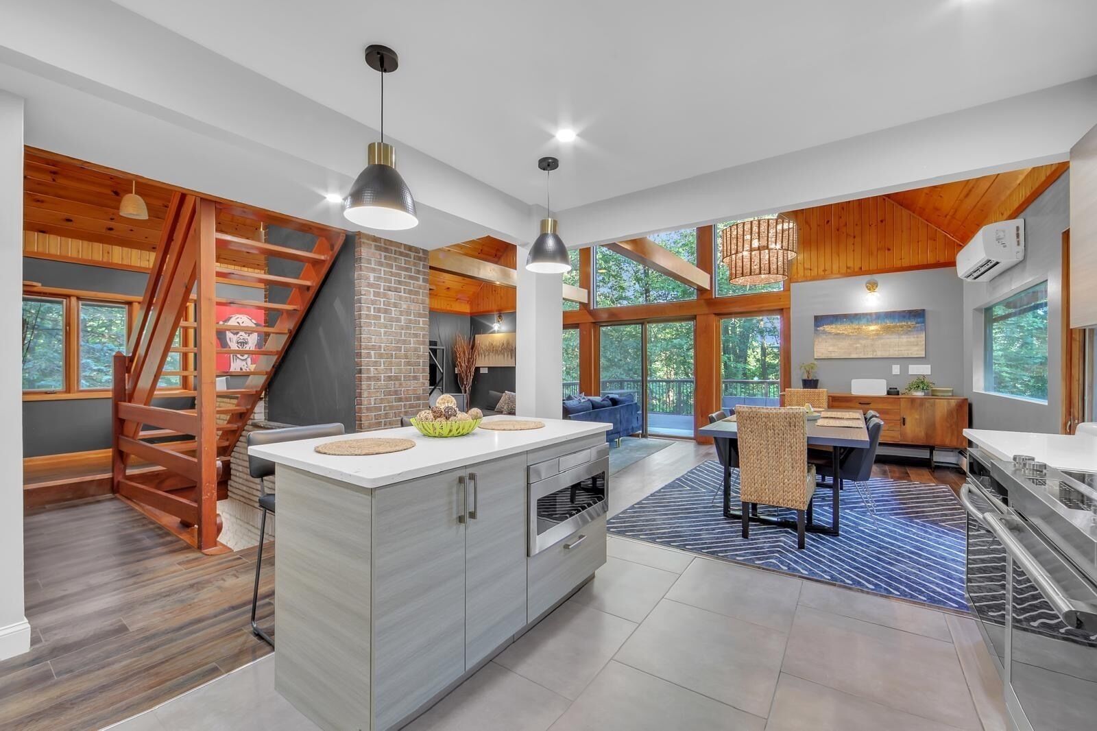 A modern kitchen with a central island, wooden accents, and large windows.