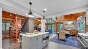A modern kitchen with a central island, wooden accents, and large windows.