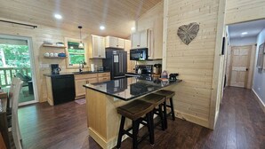 A modern kitchen with wooden cabinetry, a central island, and a view of the outdoors.
