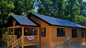 A wooden cabin with a porch, a staircase, and a flag.