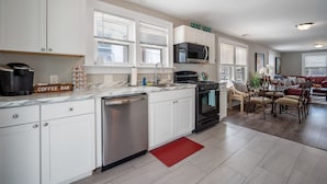 A modern kitchen with white cabinets, a coffee bar, and a dining area with a red rug. - 3BR Bayside Retreat - Beach Gear Included (Ventnor City)