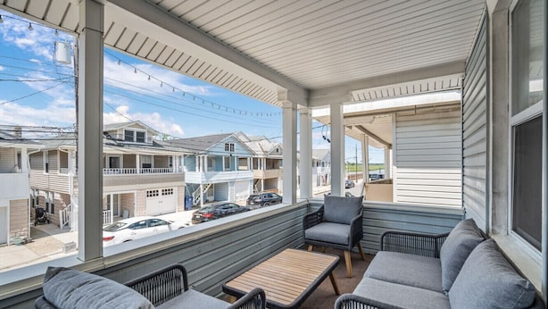 A covered outdoor seating area with wicker furniture and a view of neighboring houses. - 3BR Bayside Retreat - Beach Gear Included (Ventnor City)
