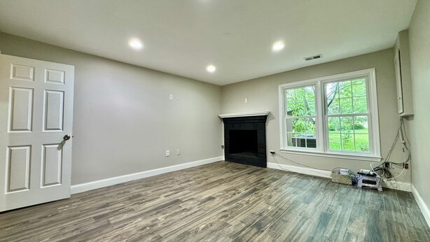 A spacious room with a fireplace, a large window, and a door. - Charming 2-bed apartment in lovely Oakton - a few miles from many universities! (Oakton)