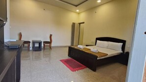 Une chambre d’hôtel avec un lit, un bureau, deux chaises et un tapis rouge.