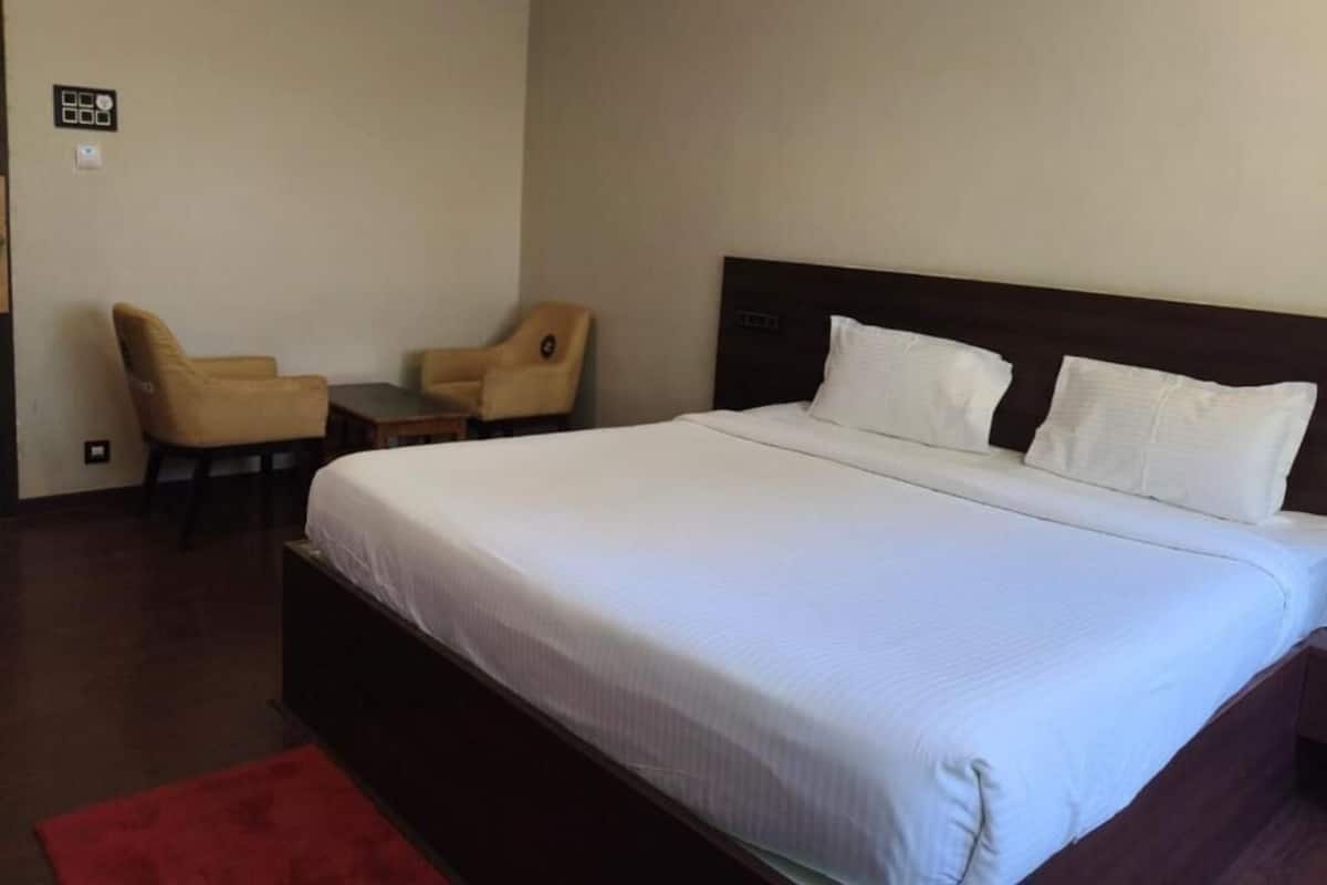 Ein Hotelzimmer mit einem großen Bett, zwei Stühlen, einem kleinen Tisch und einem roten Teppich.