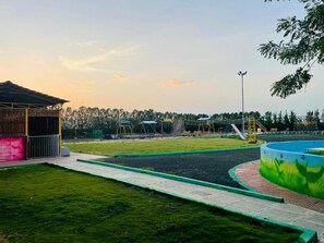 Ein Spielplatz mit Rutsche, Schaukeln und einem umzäunten Bereich.