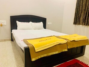 Un lit bien fait, avec du linge de lit blanc et deux serviettes jaunes posées sur le pied de lit.