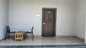 A room with a dark wooden door, a small wooden table, and two black chairs. - The Aurum Zurich Club Kalaburgi (Gulbarga)