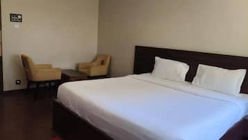 Una camera d'albergo con un letto grande, due poltrone, un tavolino e un tappeto rosso.