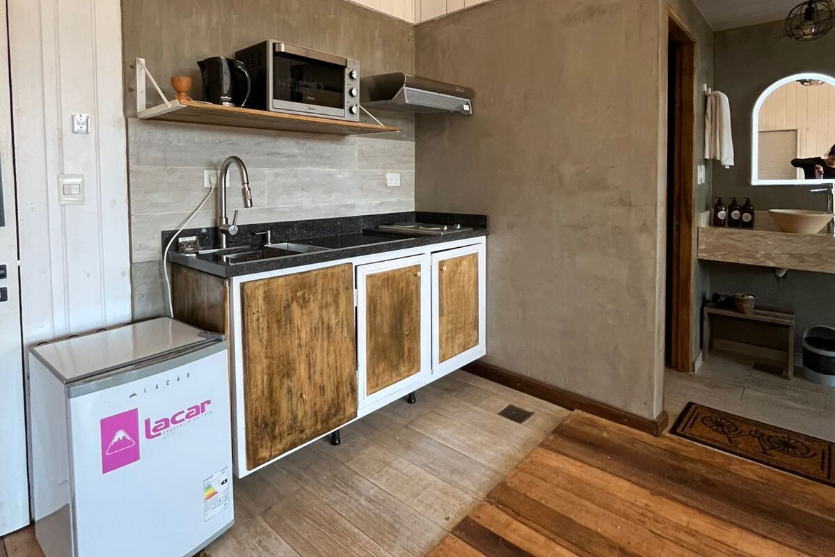 Una cocina compacta con microondas integrado, un lavamanos y armarios de madera.