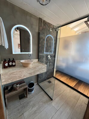 Une salle de bain moderne avec une douche à parois de verre, un comptoir en marbre et un grand miroir.