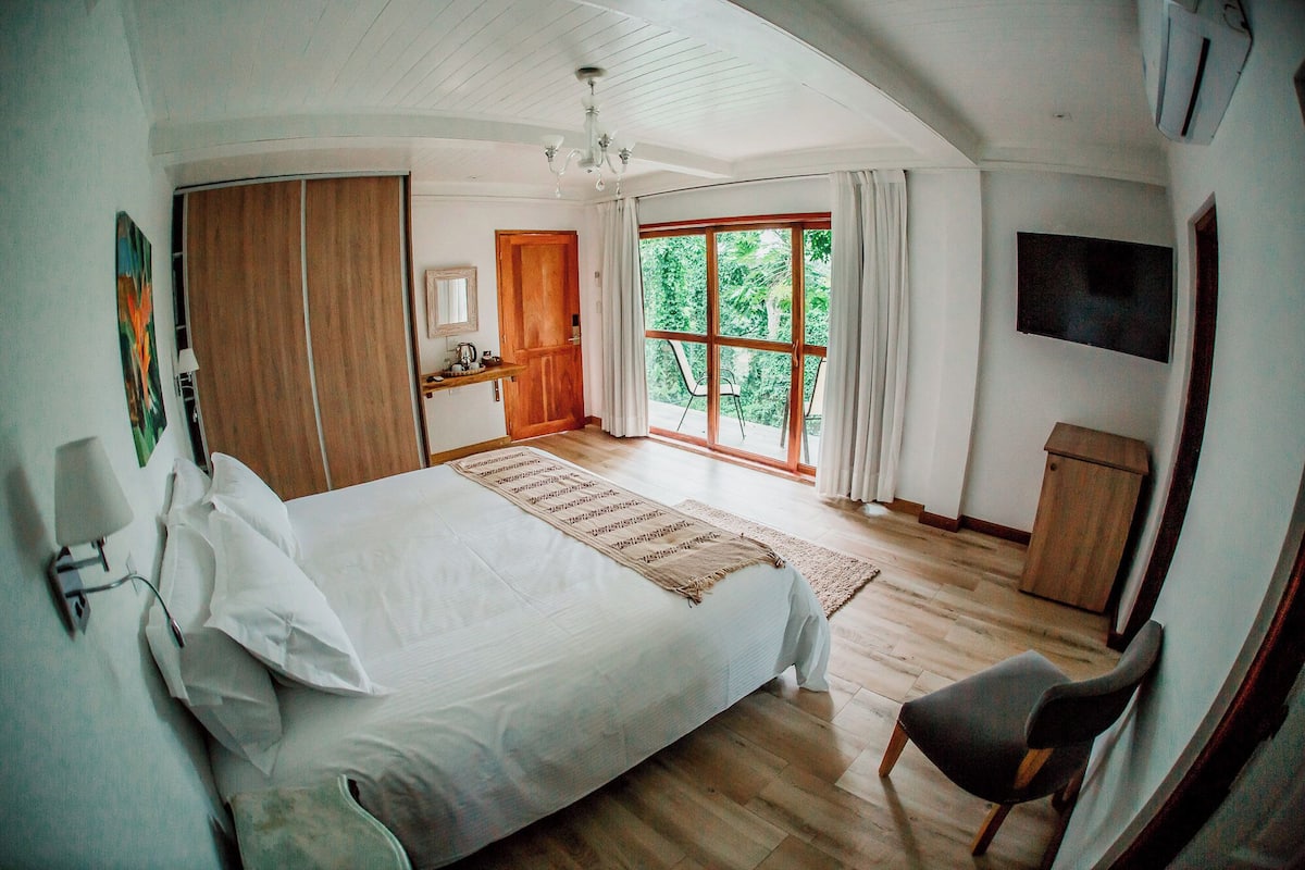 Un dormitorio con una cama grande, un escritorio, una silla y un televisor.