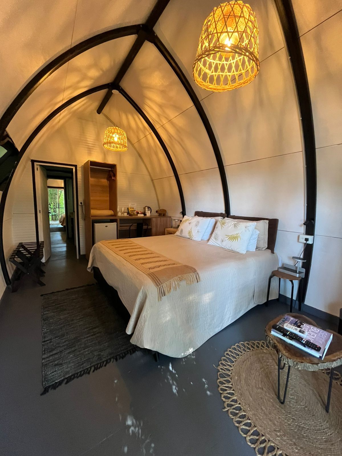 Een knus tent-achtig vertrek met een bed, nachtkastje en een hanglamp.