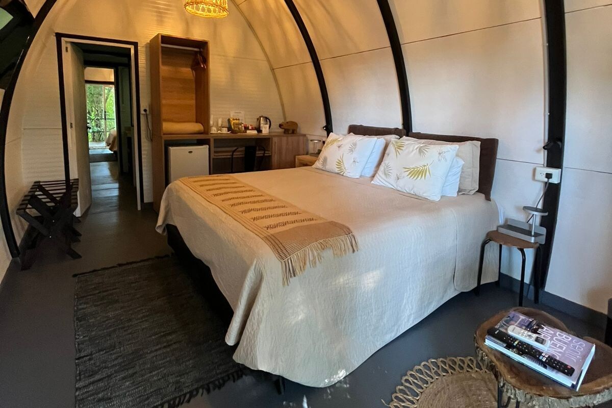 Una camera in stile tenda accogliente, con un letto, un comodino e una lampada a sospensione.
