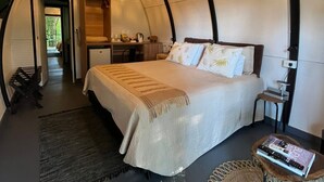 Habitació tipus tenda acollidora amb un llit, una taula de nit i una làmpada penjant.