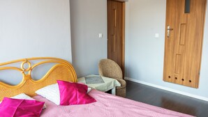 Una camera da letto con un letto, cuscini, una sedia, un tavolino e due porte in legno.