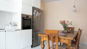 Una cucina moderna con mobili bianchi, un frigorifero in acciaio inossidabile e un tavolo con sedie.