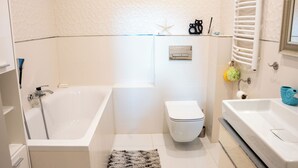 Un bagno moderno con vasca, water e lavandino.