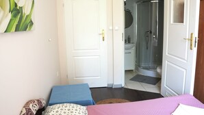 Una camera da letto con un letto, un comodino, una porta e un bagno visibile attraverso una porta aperta.