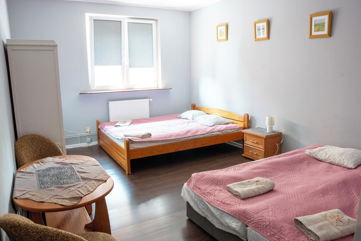 A bedroom with a bed, bedside table, chair, and a window.