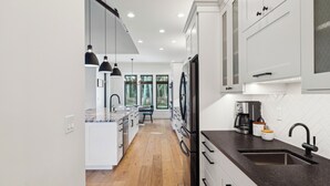A modern kitchen with white cabinets, a black countertop, and a wooden floor.