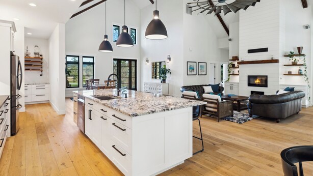 A spacious kitchen with a large island, white cabinetry, and modern pendant lighting.